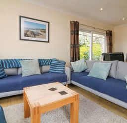 A living room with two sofas a wooden coffee table and framed pictures on the wall at Beach Lodge in Woolacombe