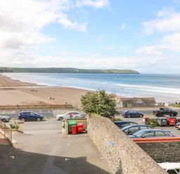 View of a beach with parked cars and a road in the foreground and hills in the background at Beach Lodge in Woolacombe