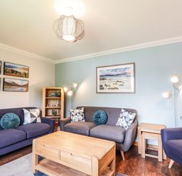 A living room with two purple sofas a purple armchair wooden coffee table and wall art at Silver Birch Lodge in Ratagan Glenshiel near Dornie