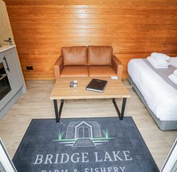 A living room with a sofa and kitchen unit at Acorn Lodge At Bridge Lake Farm & Fishery Chacombe