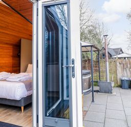 A bedroom with towels on a bed and outdoor area with hot tub at Acorn Lodge At Bridge Lake Farm & Fishery Chacombe