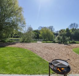 A garden with a barbecue grill and a view of water at Acorn Lodge At Bridge Lake Farm & Fishery Chacombe