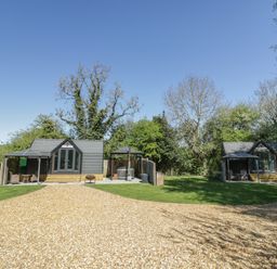 Two huts and a gravel driveway in a garden at Acorn Lodge At Bridge Lake Farm & Fishery Chacombe