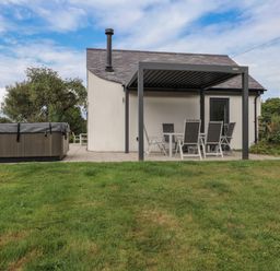 A patio area with a hot tub and seating at Pen Y Cefn in Pen Y Cefn