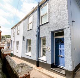 Exterior view of a two-story blue and white terraced house with a blue door at Armorel House in Dartmouth