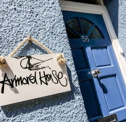 A blue front door with number 56 and a hanging sign saying Armorel House on a textured wall at Armorel House in Dartmouth