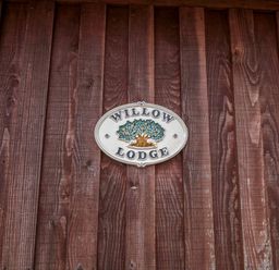 A wooden wall with a sign reading Willow Lodge near Lyme Regis