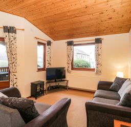 A living room with two sofas a television and patterned curtains at The Oak Lodge near Lyme Regis