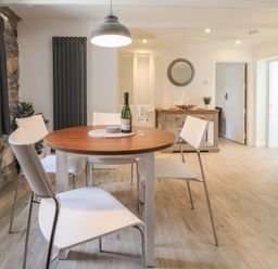 A dining area with a round table set with a bottle and glasses surrounded by four chairs at Awelfa in Newport Pembrokeshire