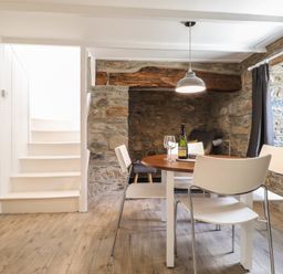 A dining area with a round table and white chairs next to a stone wall and white stairs at Awelfa Newport Pembrokeshire