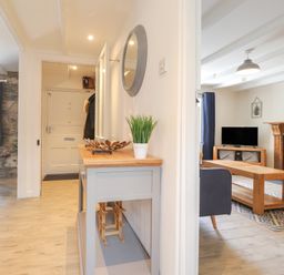 A hallway with wooden console table and a living room with TV and fireplace at Awelfa in Newport Pembrokeshire