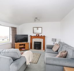 A living room with two sofas a fireplace and a television at The Little Dolphins in Rhosneigr