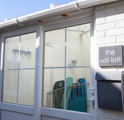 White brick exterior with a glass door a mailbox and a sign that reads the sail loft in St Ives