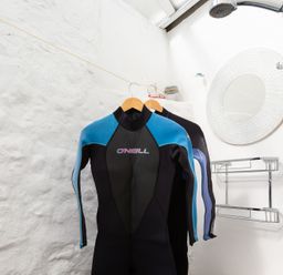 A bathroom with wetsuits hanging on a clothesline a round mirror and a shower at The Sail Loft in St Ives