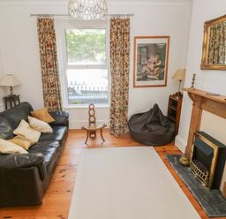 A living room with a leather sofa bean bag chair fireplace and window with curtains at Hawthorn House in Pembroke