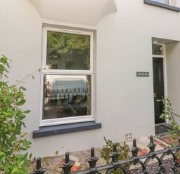 White exterior wall with a window and a black door with a sign reading Hawthorn House at Pembroke