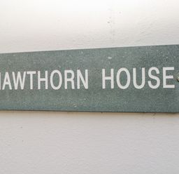 A stone plaque with the text HAWTHORN HOUSE mounted on a white wall at Hawthorn House in Pembroke