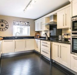 A kitchen with white cabinets black countertops stainless steel appliances and a wall clock at The Golf Apartment in Kendal