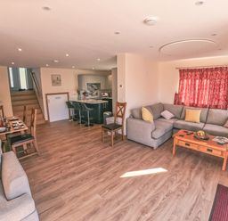 An open living room and kitchen with grey sofas and a wooden coffee table at Swallows Dip in Honiton