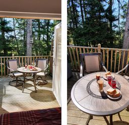 A small outdoor wooden deck with two chairs and a round table set with drinks and sandwiches at Treetops in Otterburn