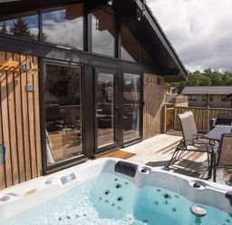 An outdoor deck area with a hot tub table and chairs attached to a wooden building at Pine Tree in Otterburn