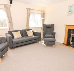 A living room with grey sofas a fireplace and yellow curtains at Broadclyst Cottage in Ottery St Mary