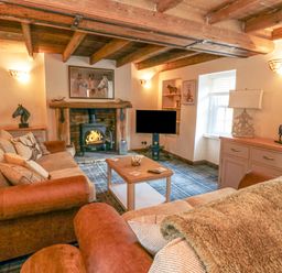 A living room with sofas a coffee table a fireplace and a television at The Nook at 29 High Street Cloughton near Burniston