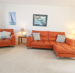 A living room with orange leather sofas side tables with lamps and framed pictures on the walls at Fairways in Wyke Regis
