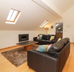 A living room with two black leather sofas a coffee table a rug a fireplace and skylights at Cholwell Barn Apartment Mary Tavy