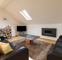 A living room with two black sofas a wooden coffee table a rug and a TV at Cholwell Barn Apartment in Mary Tavy