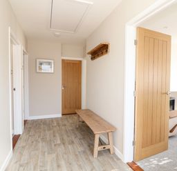 A hallway with a wooden bench a wall-mounted coat rack and wooden doors at Sunnyside in Wells-Next-The-Sea