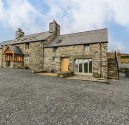 A stone house with slate roof gravel driveway wooden door and external staircase at Hen Dy Craig Yr Ronwy in Capel Celyn near Bala