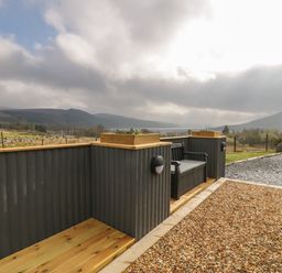 An outdoor seating area with a bench and planters surrounded by wooden panels at Hen Dy Craig Yr Ronwy in Capel Celyn near Bala