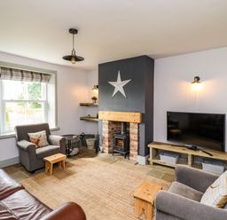 A living room with a fireplace TV sofa and armchairs at Holida Hoose in Belford