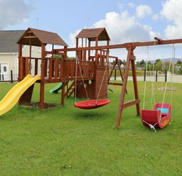 A wooden playground with slides and swings on grass at Loughanure Lake View in Loughanure County Donegal