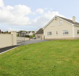 A house with a driveway and a lawn surrounded by a wall and gate at Loughanure Lake View in Loughanure County Donegal