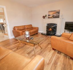 A living room with brown leather sofas a glass coffee table a fireplace and a television at Loughanure Lake View in Loughanure County Donegal