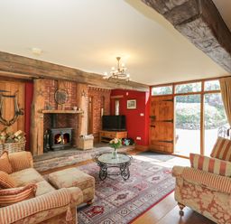 A living room with sofas a glass coffee table and fireplace at Pentre Barn in Llantilio Pertholey near Mardy