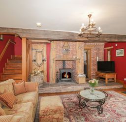 A living room with a fireplace wood stove television and floral sofa at Pentre Barn in Llantilio Pertholey near Mardy