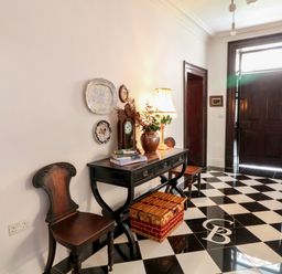 An entryway with black and white checkered floor two wooden chairs a black console table with books a lamp a clock and a basket on the floor at Carley's Bridge House Carley's Bridge near Enniscorthy County Wexford