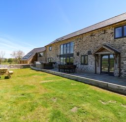 Stone exterior of a house with patio furniture and a picnic table on a lawn at Bwthyn Y Bugail Shepherds Cottage in Pedairffordd near Llanrhaeadr Ym Mochnant
