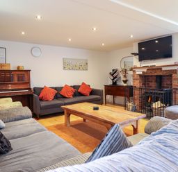 A living room with a piano, sofa, coffee table, and fireplace at Bwthyn Y Bugail (Shepherd's Cottage) Pedairffordd near Llanrhaeadr-Ym-Mochnant