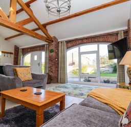 A living room with gray sofas a wooden coffee table and exposed wooden beams at Plough Cottage Little Kelk near Bridlington