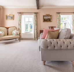 A sitting room with two sofas floral curtains and landscape paintings at Field Head House in Graythwaite near Hawkshead