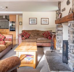 A living room with sofas and a wooden coffee table near a stone fireplace at Bull Pen Graythwaite near Hawkshead