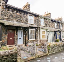 A row of stone terraced houses with different colored doors and small front gardens at Pottergill in Windermere