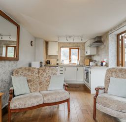 A living room with a sofa and kitchen area at Calcott Annexe in Whitchurch, Herefordshire