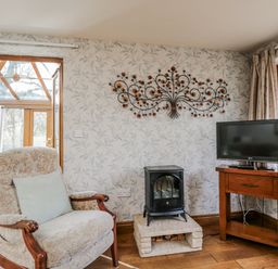 A living room with a chair and a television at Calcott Annexe in Whitchurch, Herefordshire