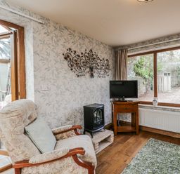 A snug with an armchair and television at Calcott Annexe in Whitchurch, Herefordshire