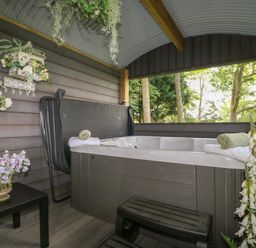 A covered outdoor hot tub with towels flowers and wall decorations at High Rigg Shepherd's Hideaway in Brampton Cumbria